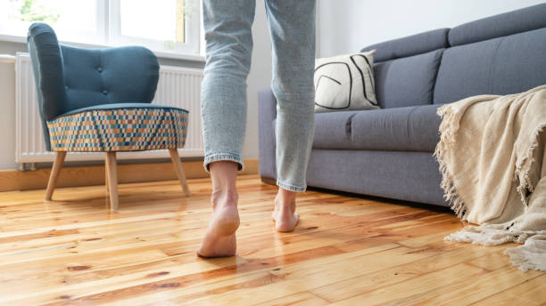 woman in jeans walking barefoot in room cropped shot of female legs walk barefoot on wooden warm floor near couch in living room at home, heating concept heat home interior comfortable human foot stock pictures, royalty-free photos & images