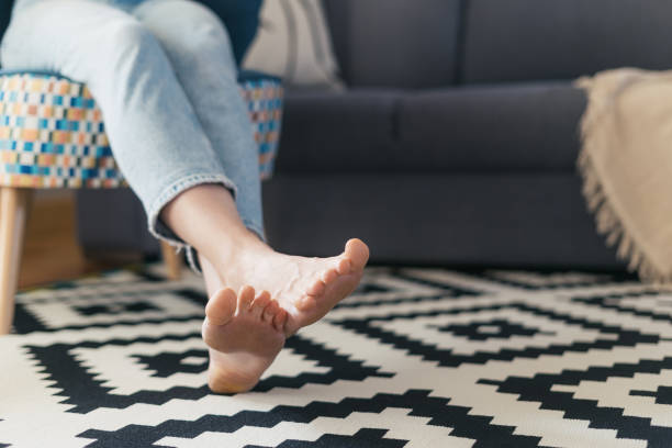 woman in jeans rest on armchair, focus on feet cropped shot of female with barefoot legs on floor carpet relaxing on comfort armchair near couch in living room at cozy apartment heat home interior comfortable human foot stock pictures, royalty-free photos & images