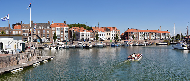 Middelburg, Netherlands - August 2022: Panoramic view of a small tourist sightseeing cruise boat sailing on the harbour near the city centre