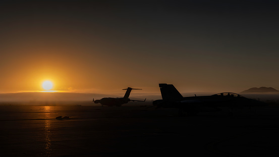 Miramar, California, USA - September 25, 2022: An FA-18 Hornet and C-17 Globemaster sit on the tarmac before the crowds arrive at the 2022 Miramar Airshow.