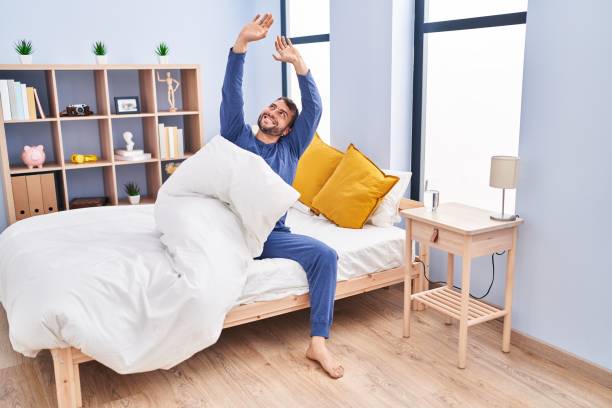 istock Young hispanic man waking up stretching arms at bedroom 1437925777