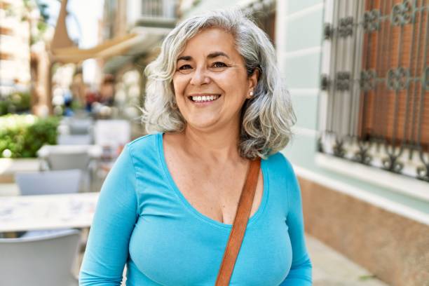 中年の灰色の髪の女性は、街に立って幸せそうに微笑んでいます。 - beautiful senior woman ストックフォトと画像