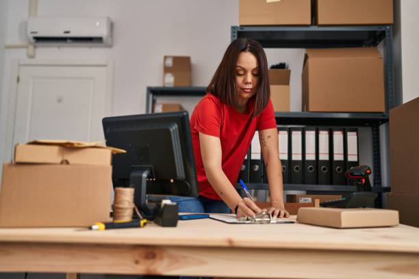 istock Young beautiful hispanic woman ecommerce business worker writing on document at office 1437929659
