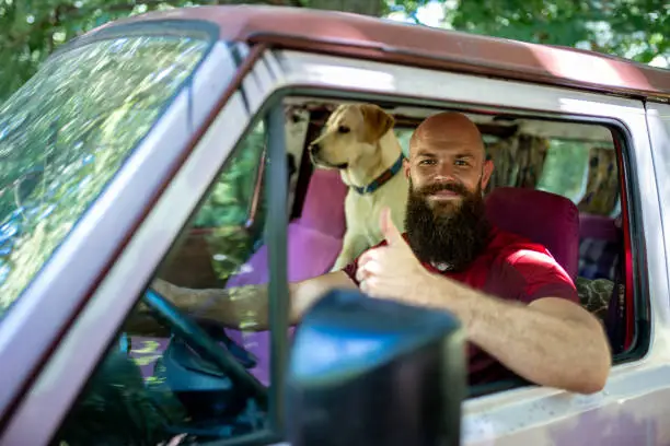 Photo of Caucasian male in a car with his Golden Retriever