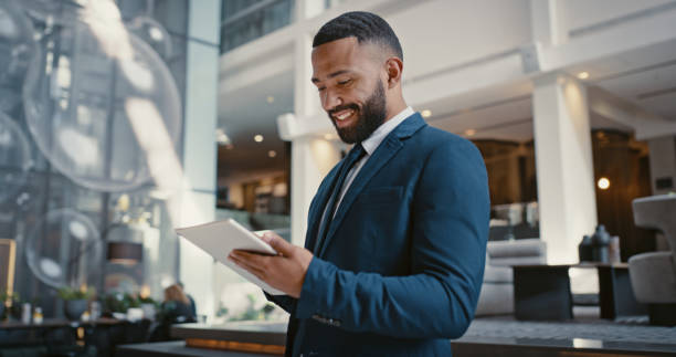 empresario, tableta digital o planificación estratégica en el vestíbulo de conferencias del hotel o en la sala de viajes del aeropuerto. sonrisa feliz, trabajador corporativo o aplicación de tecnología para presupuestar las finanzas de la empresa o pr - hotel fotografías e imágenes de stock