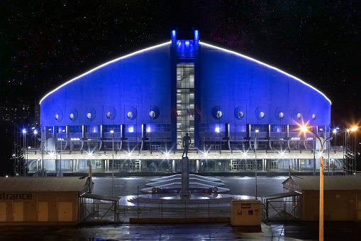 Krasnoyarsk, Russia - 24 October, 2022: Night view on Ivan Yarygin Sports Palace in blue street illumination. Located in Krasnoyarsk, Russia, on an island in the Yenisei River.