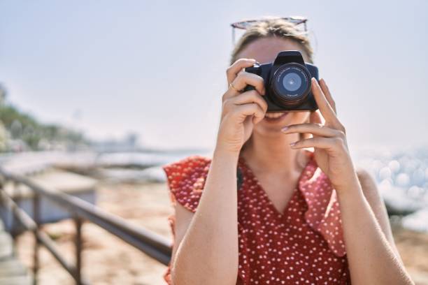istock Young blonde girl smiling happy using camera at the beach 1437932128