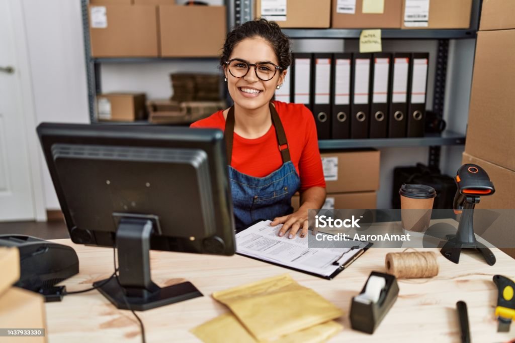 Young latin woman ecommerce business worker writing on clipboard at office Supply Chain Stock Photo