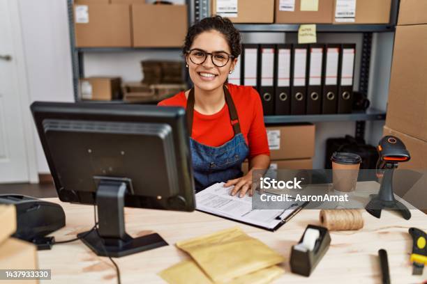 Young Latin Woman Ecommerce Business Worker Writing On Clipboard At Office Stock Photo - Download Image Now