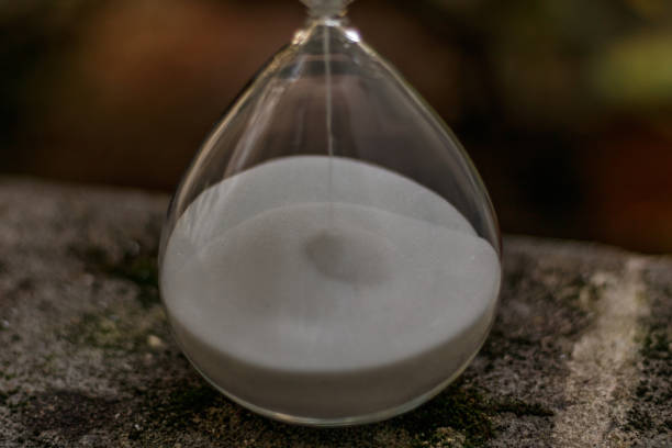 istock Close up on an hourglass placed on a stone surface covered with moss 1437933986