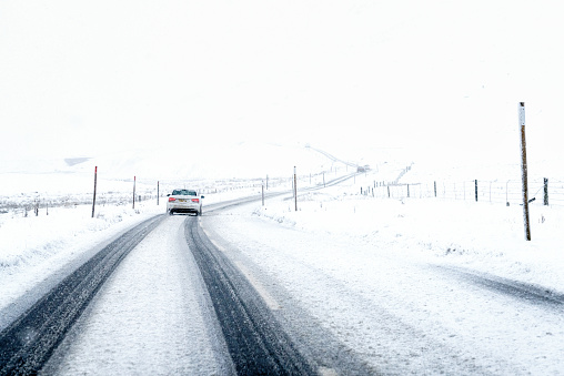 A driver's perspective during a journey on a Scottish country road, with falling snow covering much of the road surface.