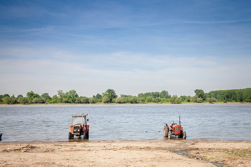 Panorama of the Danube river in Serbia with tractors on a beach during a sunny summer afternoon in Stari Slankamen, Serbia. The Danube is Europe's second-longest river. It is located in Central and Eastern Europe.