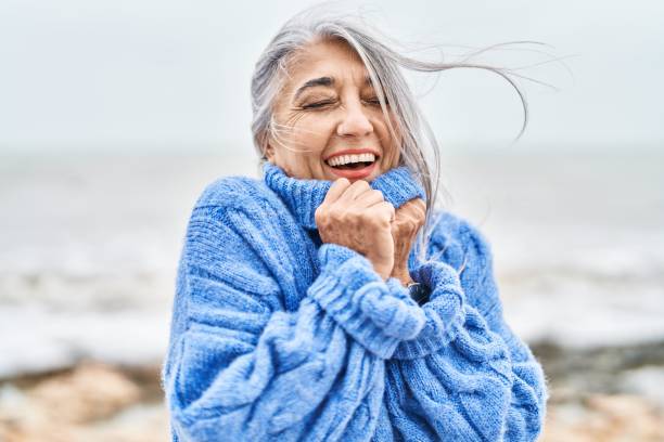 海辺に立つ自信に満ちた笑顔の中年の白髪の女性 - beautiful senior woman ストックフォトと画像