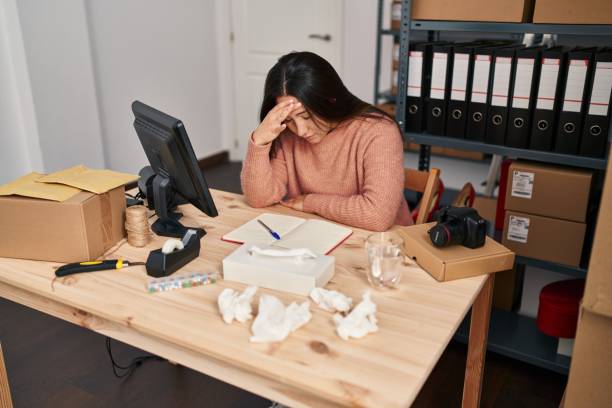 istock Young hispanic woman ecommerce business worker with headache at office 1437936512