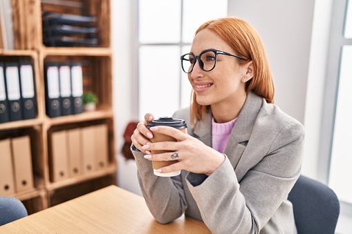 Young caucasian woman business worker smiling confiden drinking coffee at office