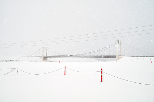 Suspension bridge with car in snowfall