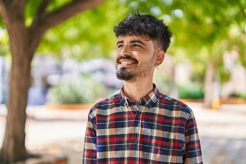 Young hispanic man smiling confident looking to the side at park