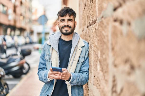 istock Young hispanic man smiling confident using smartphone at street 1437941985