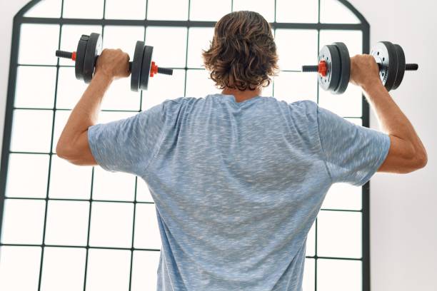 istock Middle age caucasian man on back view training using dumbbells at sport center 1437943223