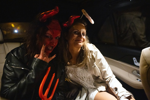 Friends riding in a taxi to a Halloween party.