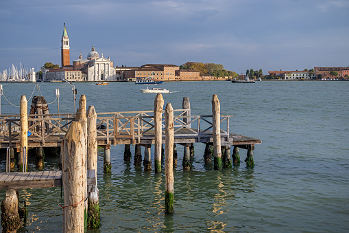 Venice, Italy - October 10th 2022: View to the old church San Giorio Maggiore with a a pier in the harbor in the foreground in the center of the old and famous Italian city Venice
