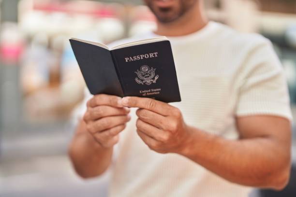 istock Young hispanic man smiling confident reading passport at street 1437943816