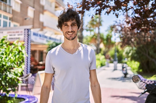 Young hispanic man smiling happy standing at the city.