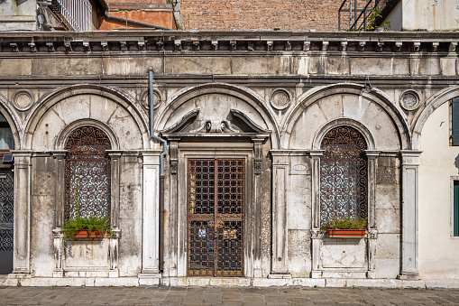 Venice, Italy - October 10th 2022:  Facade of a old house whit door and windows covered by artistic cast iron grids in the center of the old and famous Italian city Venice