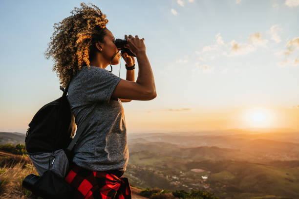 donna zaino in spalla che usa il binocolo - freedom sunset landscape travel foto e immagini stock