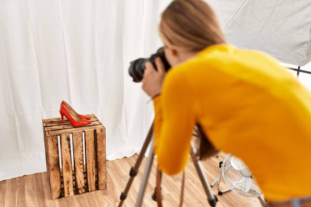 fotógrafo jovem da mulher caucasiana que faz a foto do sapato do salto alto no estúdio de fotografia - high heels flash - fotografias e filmes do acervo