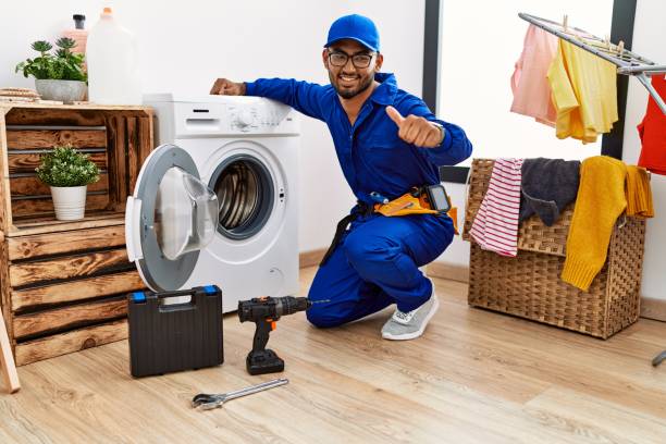 istock Young indian technician working on washing machine approving doing positive gesture with hand, thumbs up smiling and happy for success. winner gesture. 1437948910