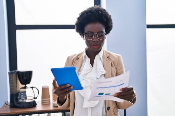 istock Young african american woman business worker using touchpad reading document at office 1437949071