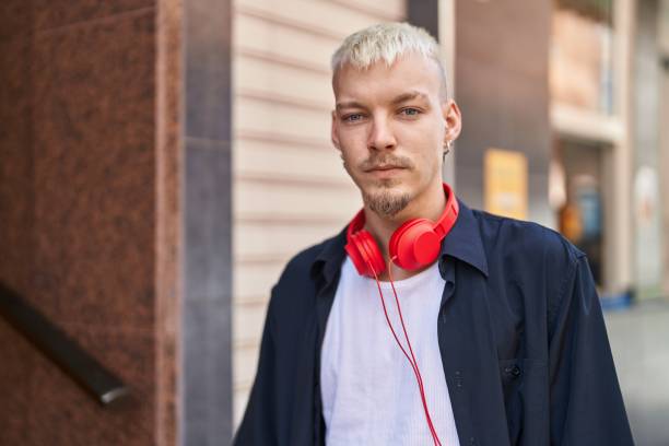 Young caucasian man wearing headphones with serious expression at street stock photo