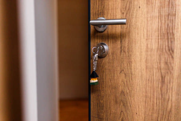 istock Open door and door handle with a key and a keychain shaped house 1437949683