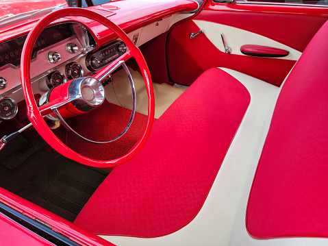 Bright red and white vintage car interior with bench seat and steering wheel