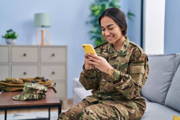 istock Young hispanic woman army soldier using smartphone at home 1437951333