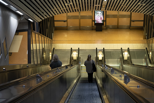 Stockholm, Sweden - August 27, 2021: Perspective view of two woman going down on escalators to subway platform in Stockholm Sweden August 27, 2021.