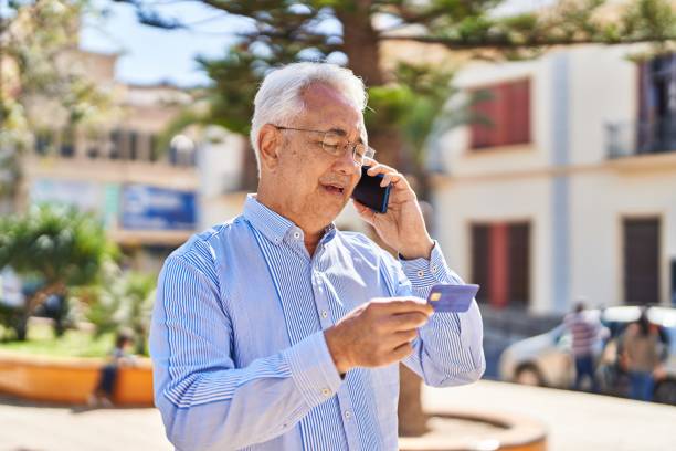 istock Senior man talking on the smartphone and using credit card at park 1437952540