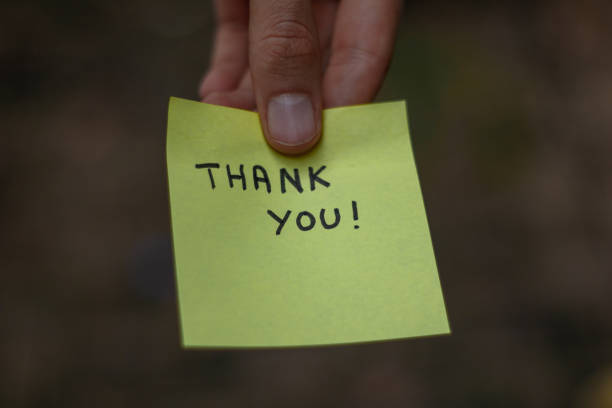istock Close up on a yellow sticky note saying thank you  held by a hand 1437952745