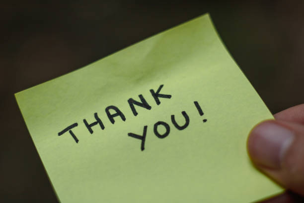 istock Close up on a yellow sticky note saying thank you  held by a hand 1437952748