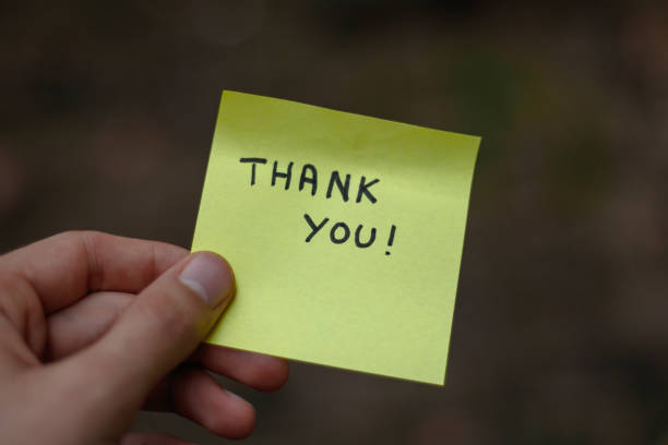 istock Close up on a yellow sticky note saying thank you  held by a hand 1437952751