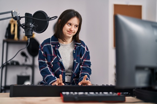 Young woman with down syndrome musician playing piano keyboard at music studio