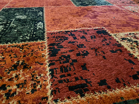 An orange prayer mat with a mosque building motif on a blue carpet