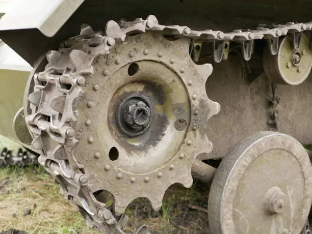 Rubberized wheels of ancient armored vehicles. Metal tracks on a tank from the Second World War. A tank painted in camouflage color on a forest road.