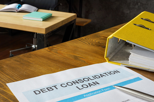 Debt consolidation loan application near a yellow folder.