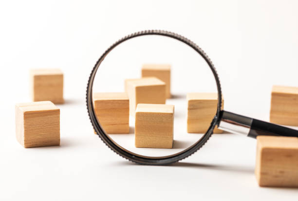Wooden cubes with magnifier on white background.