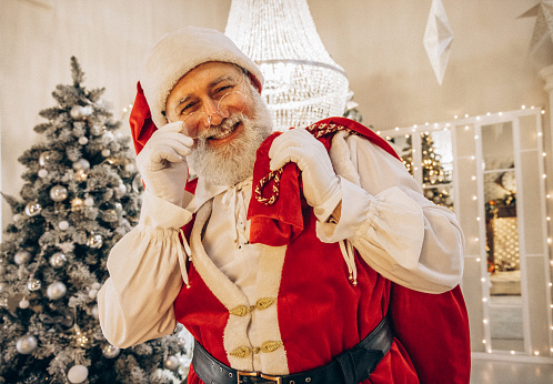 Santa Claus / Father Christmas sitting in his grotto holding a gift wrapped present for you.