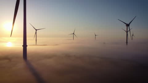 Aerial view of wind turbines in the early morning fog.
