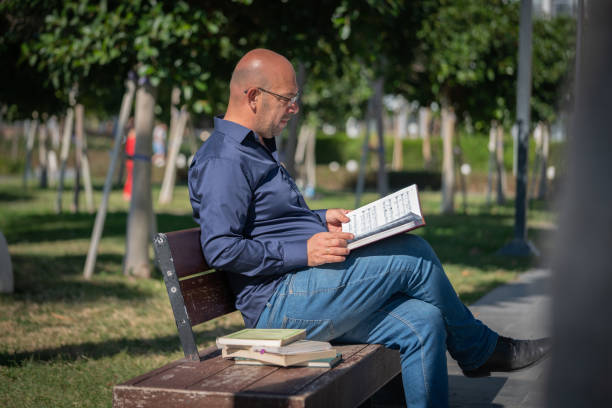 Hispanic man sitting in a park reading a book
