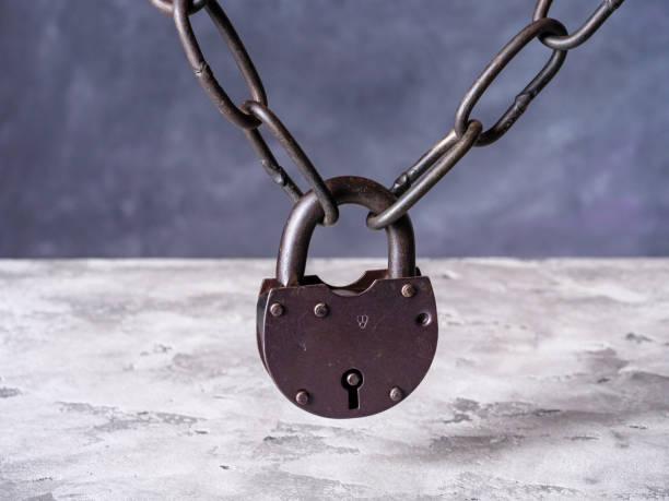 istock Old chain closed with a rusty padlock hangs above the concrete table 1437967040